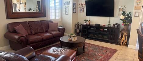A living room with a brown leather sofa, a coffee table, a TV, and a fireplace.