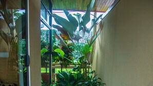 A narrow indoor pool with tiled flooring and wooden borders, surrounded by lush green plants and a wooden ceiling.