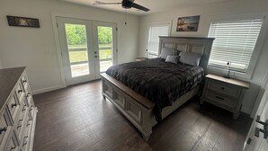 A bedroom with a bed, a ceiling fan, a nightstand, a dresser, and a window with blinds.