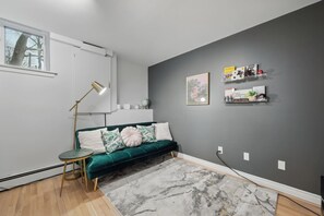 Uma sala de estar moderna com um sofá verde, um tapete de mármore e uma parede de destaque cinza.