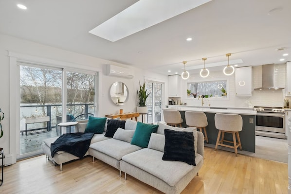 A modern kitchen with a central island, bar stools, and a dining area with a round table.