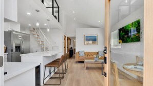 A modern kitchen with a built-in refrigerator, a dining area with a sofa and chairs, and a living room with a TV and a painting. - Brand new Cottage, putting green, private patio (Thousand Oaks)