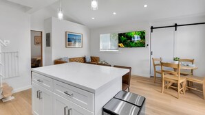 A modern kitchen with white cabinetry, a central island, and pendant lighting. - Brand new Cottage, putting green, private patio (Thousand Oaks)