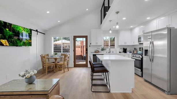 A modern kitchen with a central island, stainless steel appliances, and a dining area with a table and chairs. - Brand new Cottage, putting green, private patio (Thousand Oaks)