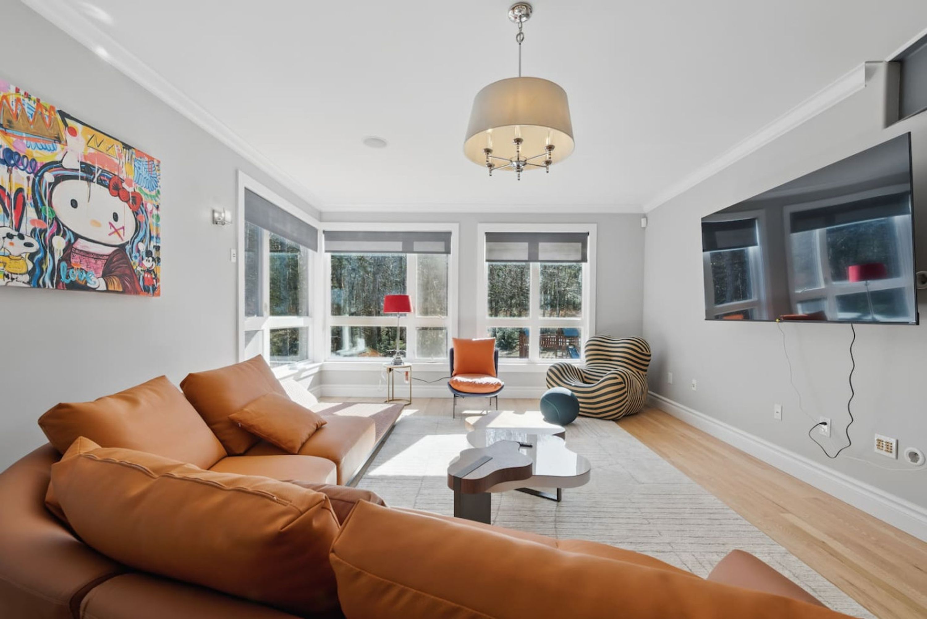 A modern living room with a large sofa, a coffee table, and a television mounted on the wall.