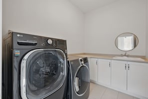 A laundry room with two LG washing machines, a sink, and a mirror. - Private Lakefront Mansion on Schmidt Lake (Hammonds Plains)