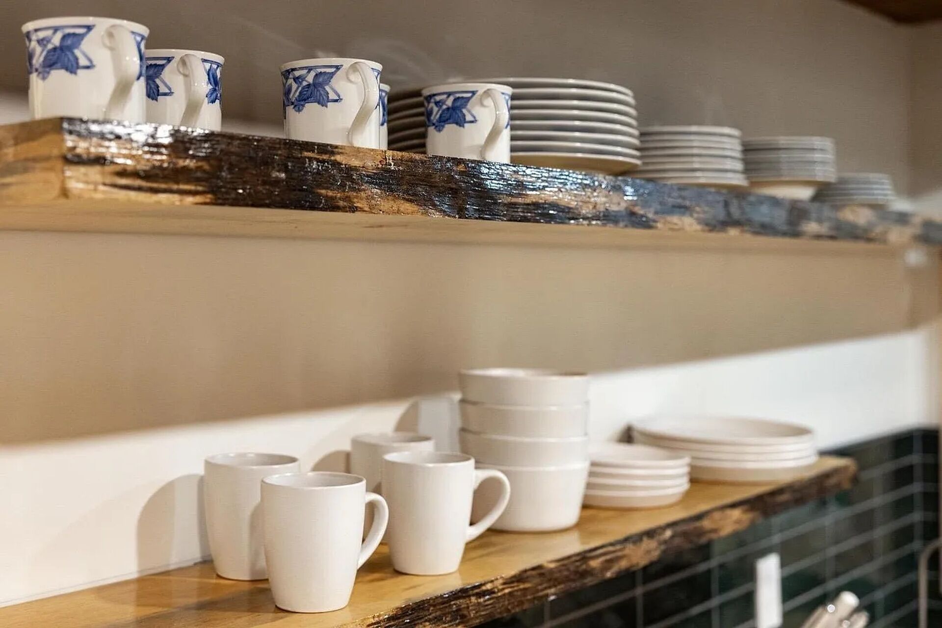 Un estante de cocina con tazas blancas y azules y platos apilados.