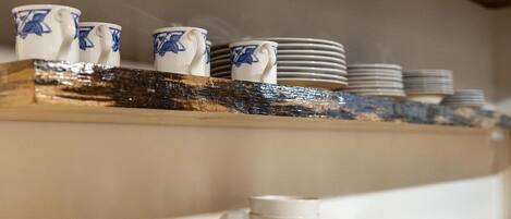 Un estante de cocina con tazas blancas y azules y platos apilados.