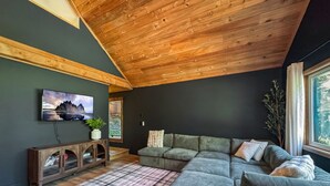 Un salon moderne avec un canapé d’angle, un meuble en bois et une grande fenêtre.