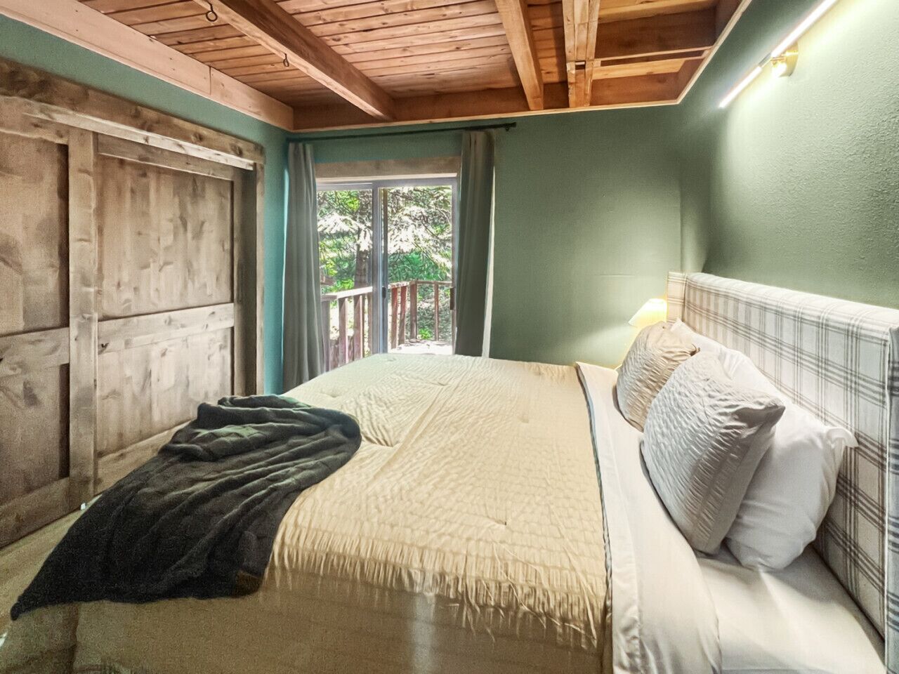 A bedroom with a bed, a window, and a view of greenery outside.