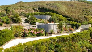 A hillside garden with a wooden staircase leading up to a white building. - 26 Waves - sleeps 4 guests  in 1 bedroom (Watergate Bay)