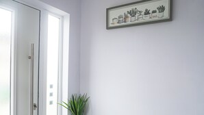 Ein Zimmer mit einer Tür, einem gerahmten Pflanzenbild und einem Blumentopf auf dem Boden.