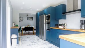 Eine moderne Küche mit blauen Schränken, einem Edelstahlkühlschrank und einer Holz Arbeitsplatte.