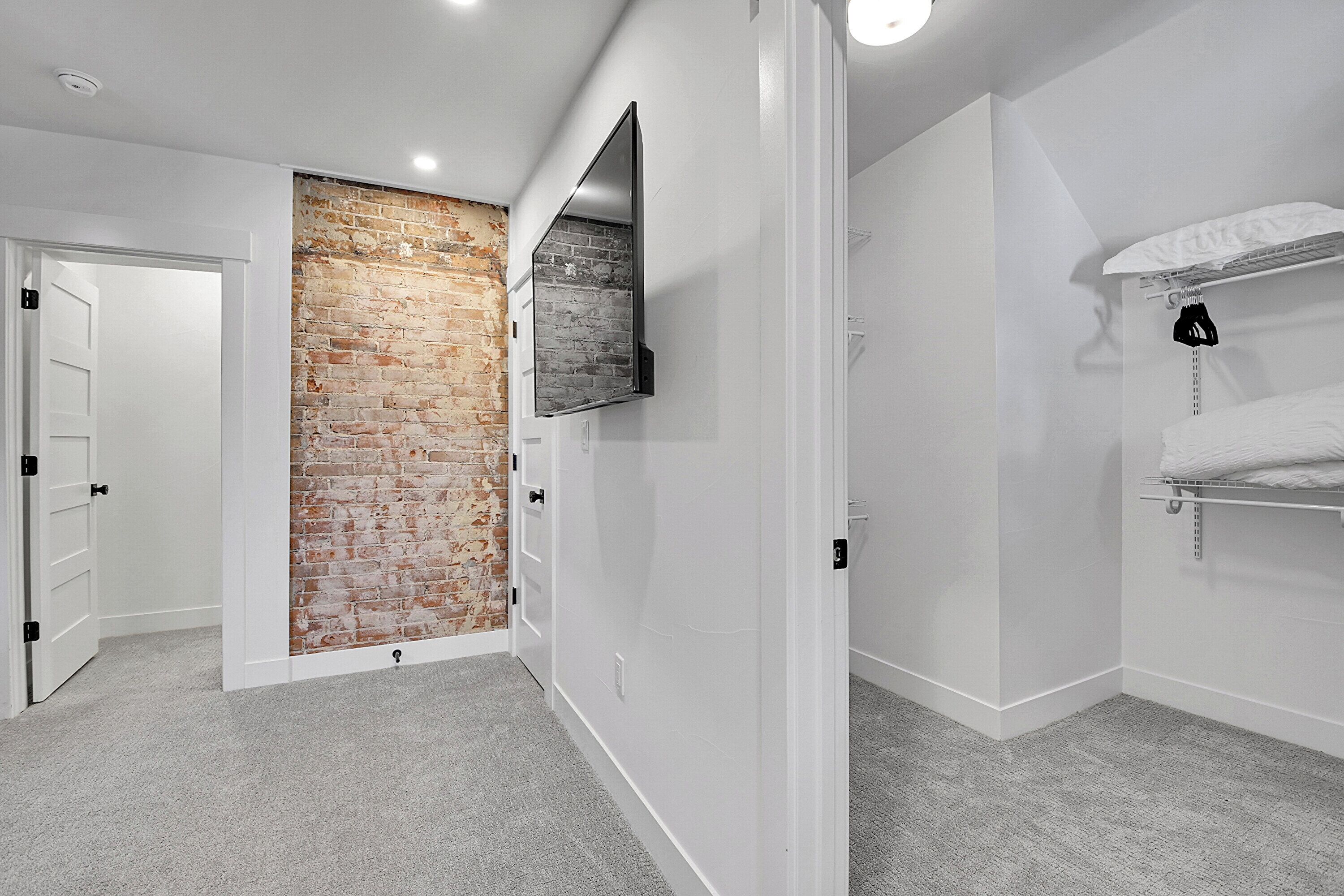 A modern bathroom with a brick accent wall, a mounted mirror, and a towel rack.