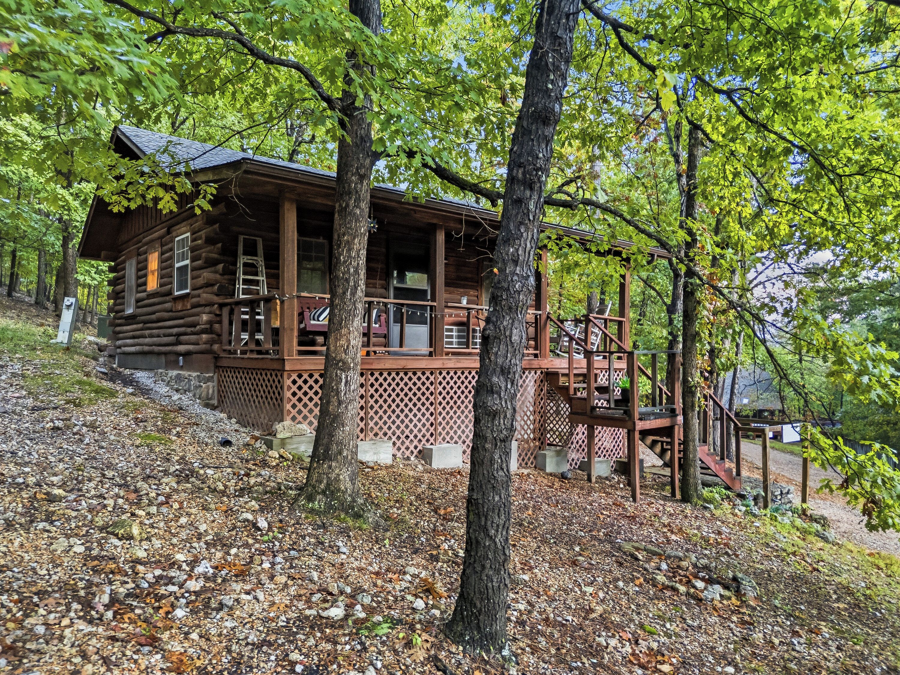 A wooden cabin with a porch and a staircase leading to a deck.