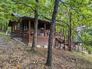 Uma cabana de madeira com varanda e escadaria para um deck.