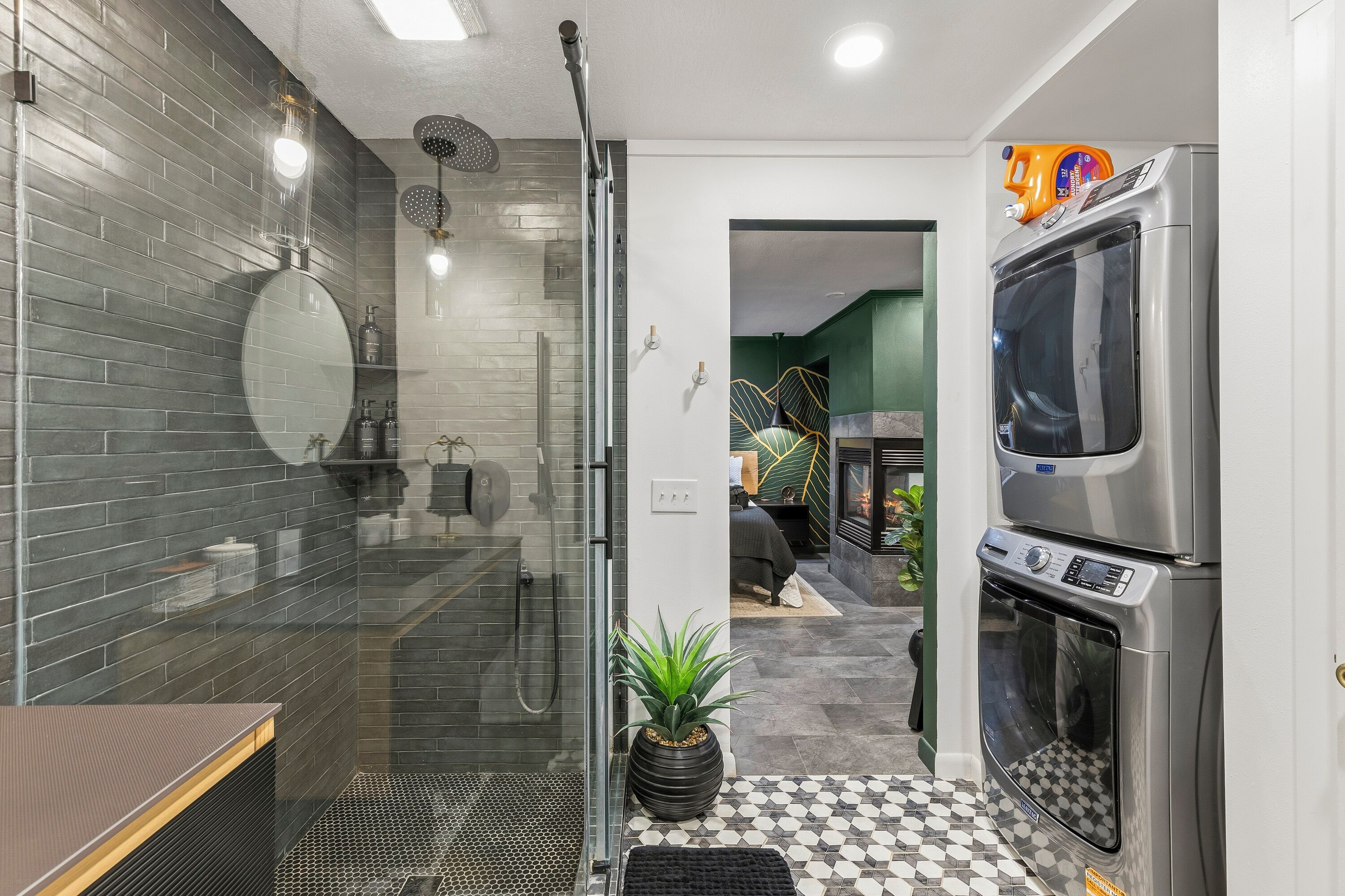 A modern bathroom with a glass shower enclosure, a built-in toilet, and a stainless steel washing machine.