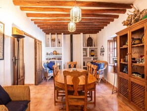 A dining area with a wooden table and chairs, surrounded by shelves with decorative items. - Beautiful rural house with swimming pool and barbecue (Cozvíjar)