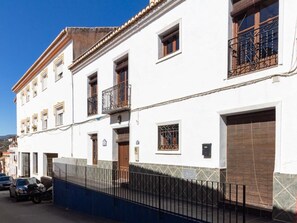 A white building with multiple windows and balconies, a gated entrance, and a parked motorcycle. - Beautiful rural house with swimming pool and barbecue (Cozvíjar)