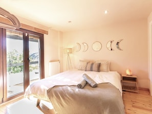 A bedroom with a large bed, a floor lamp, a heater, and a view of the outdoors.