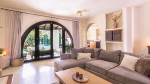 A living room with a grey sofa, wooden coffee table, and a view of a pool through a glass door. - Beautiful house with pool in the heart of the Lecrín Valley (Restábal)