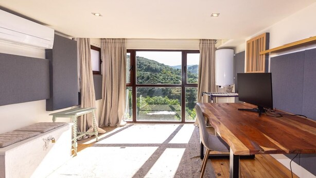 A room with a large window, a wooden desk, a television, and a radiator. - Beautiful house with pool in the heart of the Lecrín Valley (Restábal)