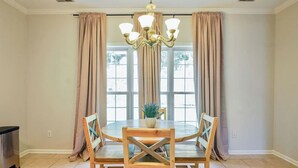 A dining area with a round table, four wooden chairs, a chandelier, and a window with curtains. - Save Big! Kent Terrace - 3br in Alabaster (Alabaster)