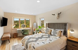 A bedroom with a large bed, a desk, a chair, a TV, and a bull skull decoration. - Pulitzer Hillside Retreat - Hot Tub - Valley Views - Near Plaza & Ski Santa Fe (Santa Fe)