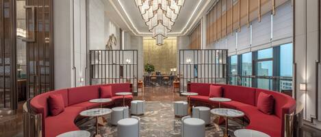 A spacious lobby with red seating, marble flooring, and a large chandelier.