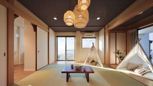 Une pièce de style japonais traditionnel, avec un sol recouvert de tatamis, une table en bois, un luminaire suspendu en rotin et une vue sur la ville grâce à de grandes fenêtres.