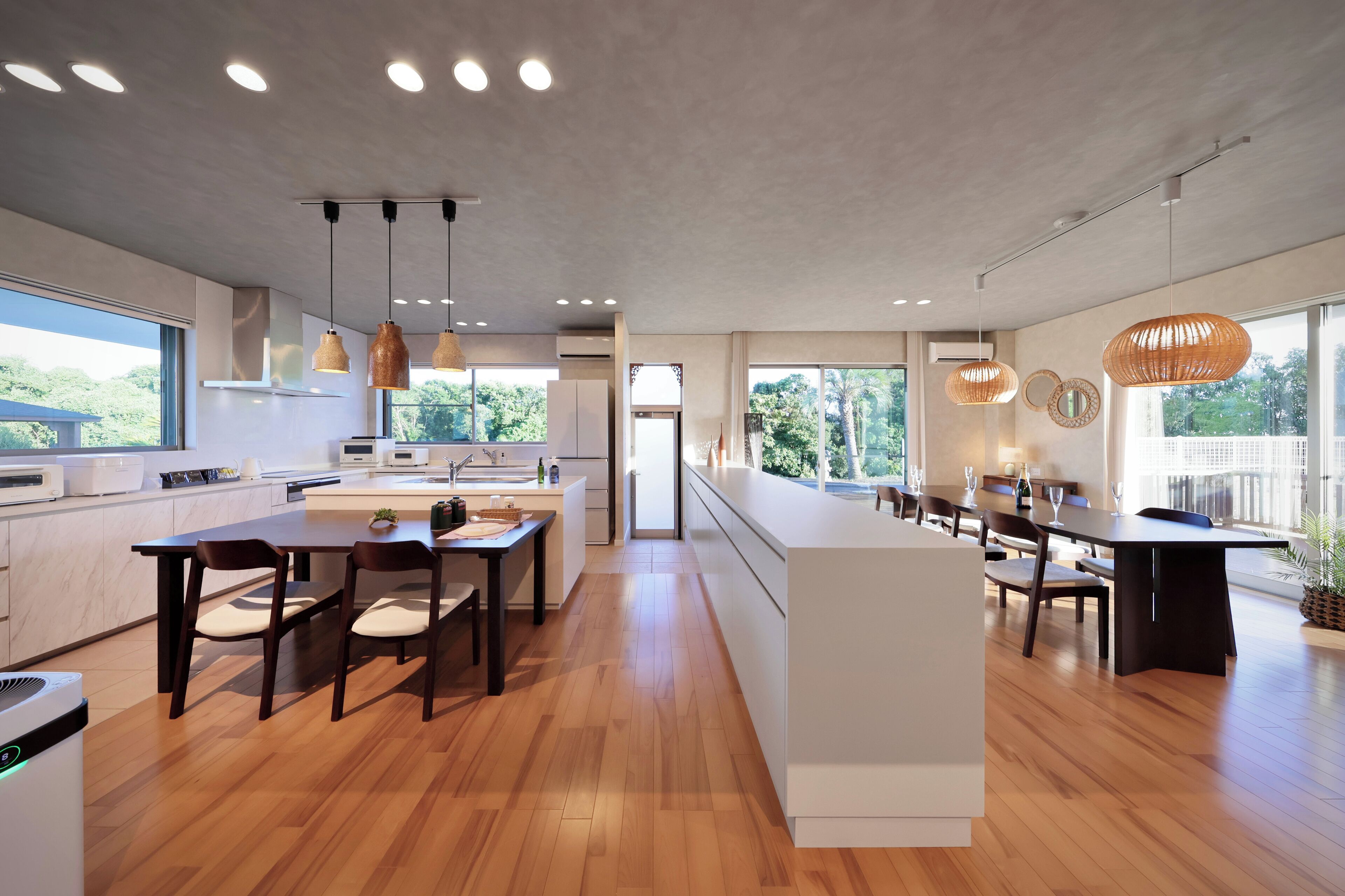 Een moderne keuken met houten vloeren, hanglampen en een groot eiland.
