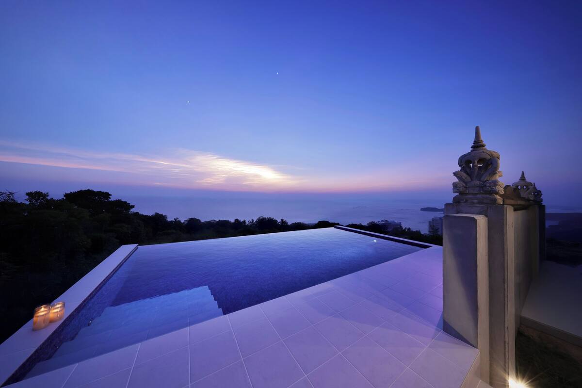A rooftop pool with a view of the ocean at dusk.