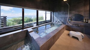 Une salle de bain moderne dotée d’une grande fenêtre, d’un jacuzzi et d’une douche.