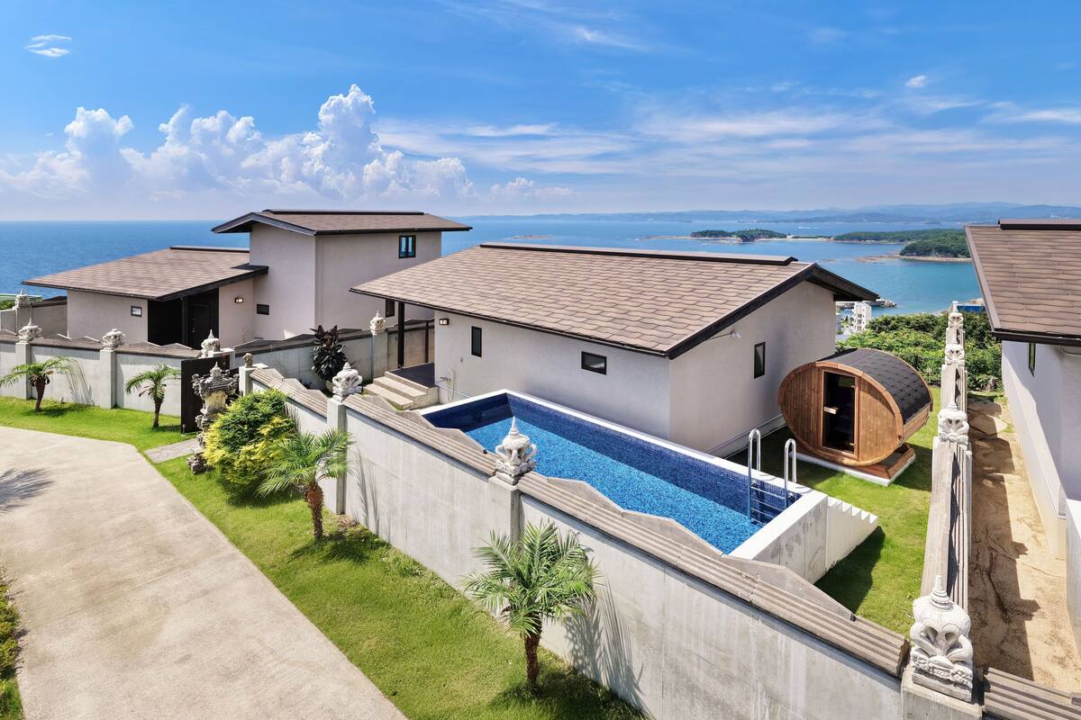 A modern villa with a swimming pool, a sauna, and a view of the sea.