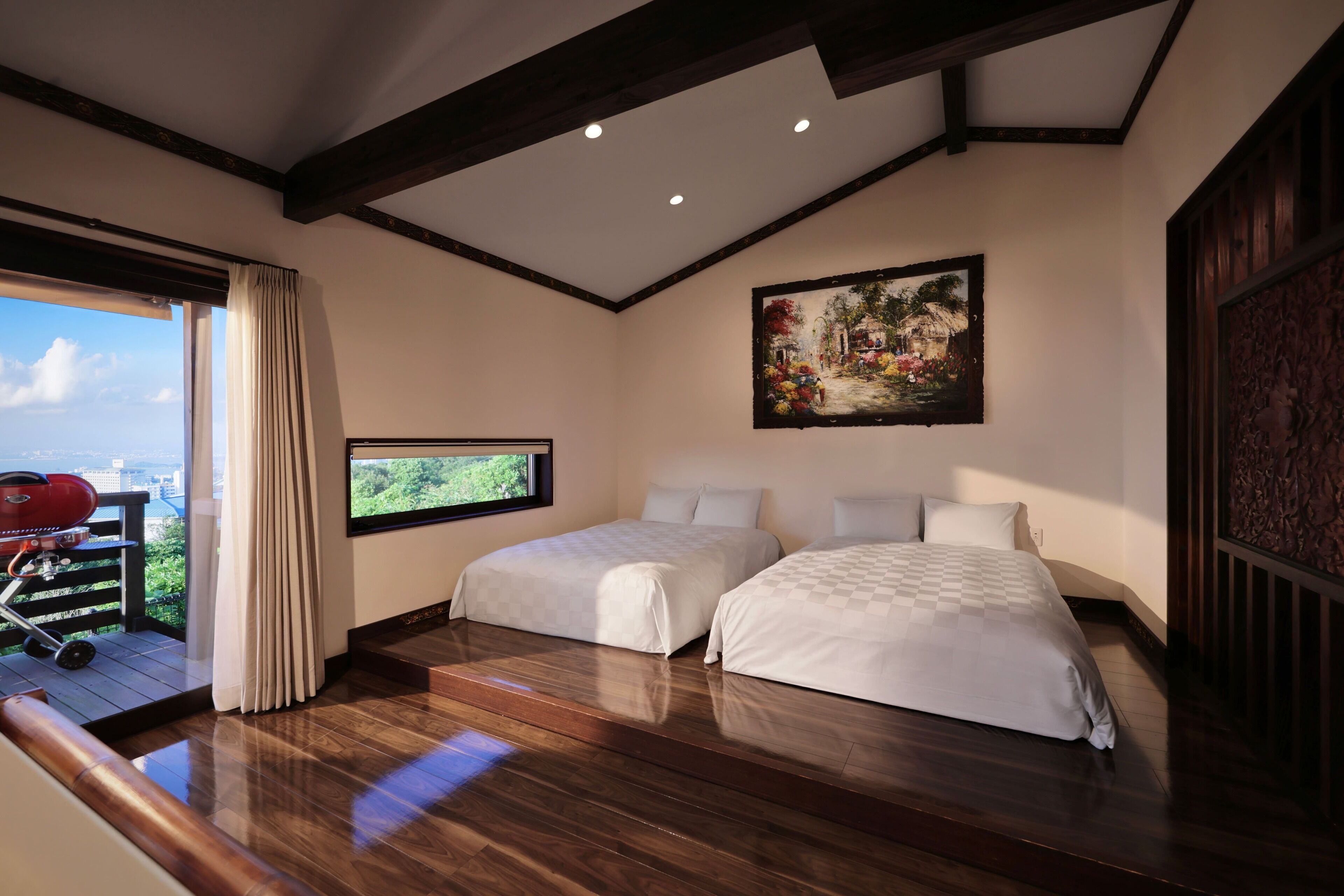 Un dormitorio con dos camas, un ventanal grande y un cuadro en la pared.