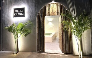 An entrance to a hotel named 'Villas K'aanab' with a bamboo archway and potted plants. - Villas K'aanab (Celestún)
