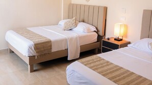 Une chambre d’hôtel avec deux lits, une table de chevet avec une lampe et un élément décoratif fixé au mur.