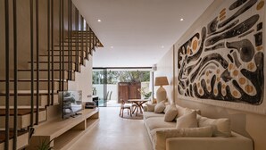 Een moderne woonkamer met een trap, een groot abstract schilderij en een bank.