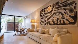 Een moderne woonkamer met een beige bank, een houten eettafel en een groot abstract schilderij aan de muur.