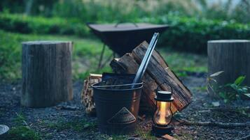 En metallhink märkt med texten ”Galvaniserad hink”, med en metallsked inuti, placerad på en grusgång med en tänd lykta i närheten.