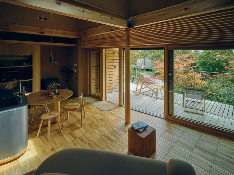 Een modern interieur met een houten vloer, een ronde eettafel en een keukenhoek.