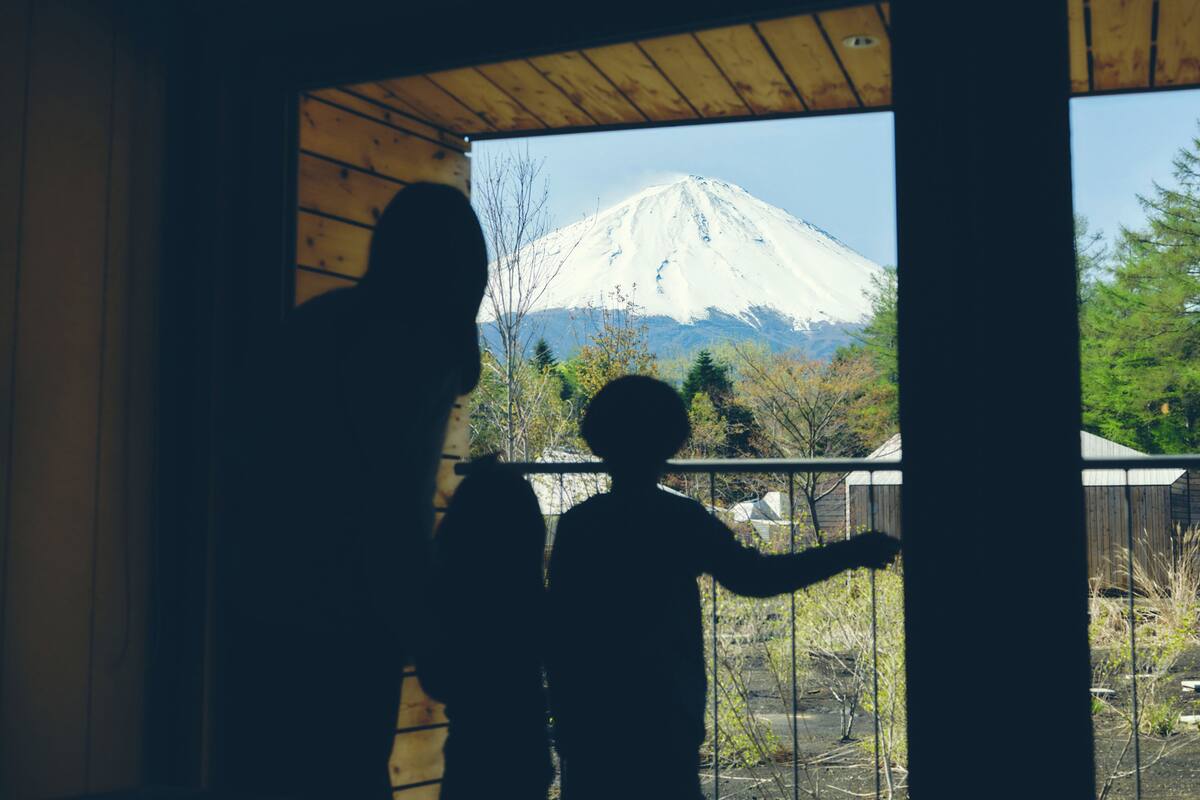 On aperçoit la silhouette de deux personnes devant une fenêtre, avec en arrière-plan une montagne enneigée.