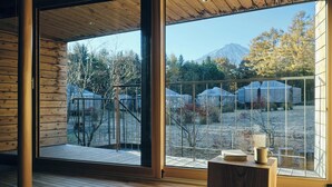 Amplia habitación con ventanas grandes que ofrecen vistas a un paisaje montañoso y un jardín cercado.