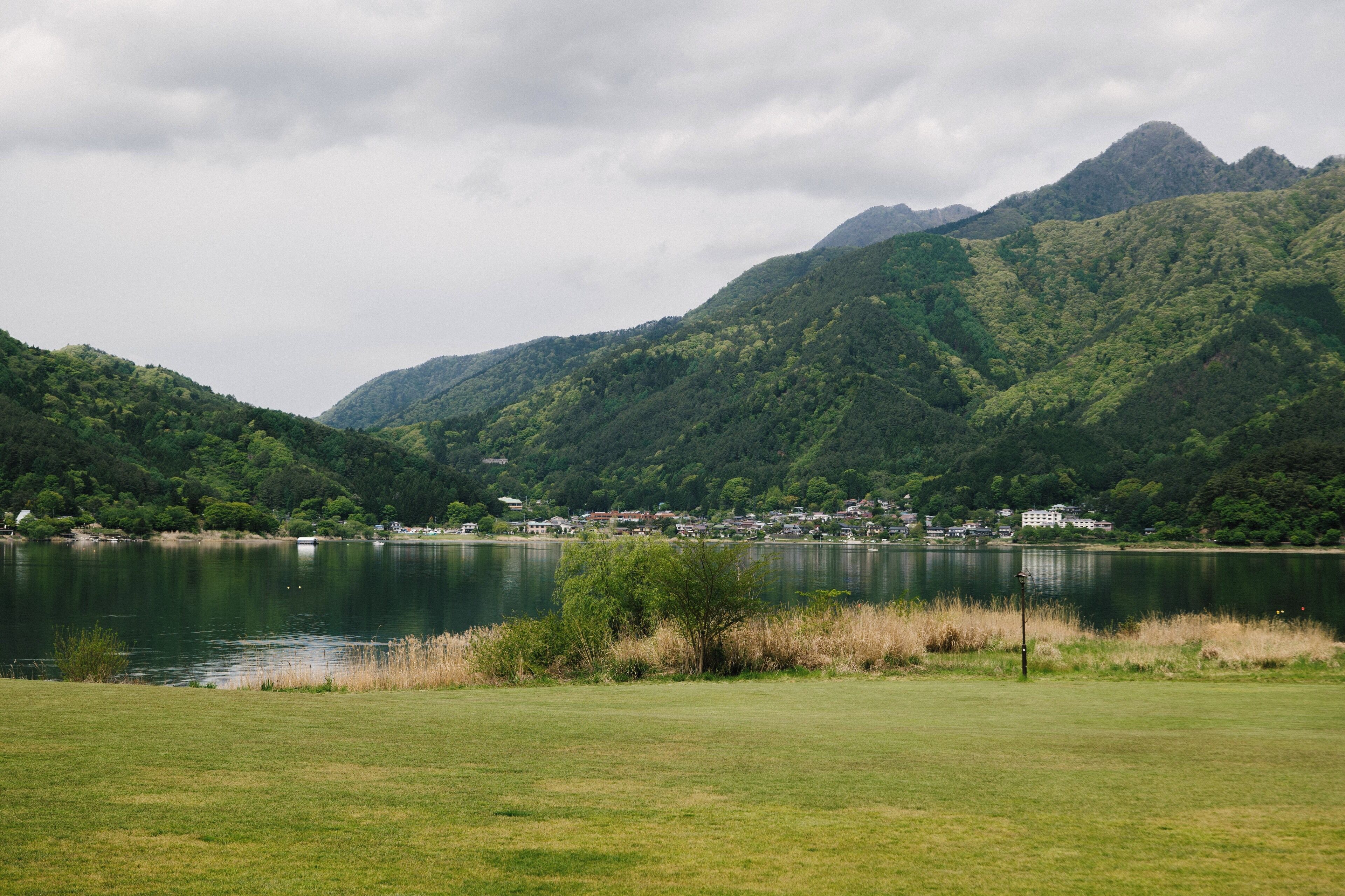 A lake surrounded by lush green hills and a small settlement.