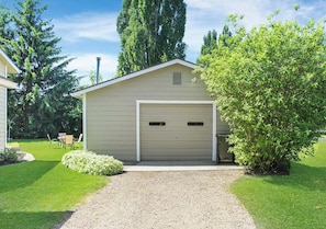 Ein eingeschossiges Gebäude mit Garage, umgeben von einem gepflegten Rasen und einem kleinen Baum.