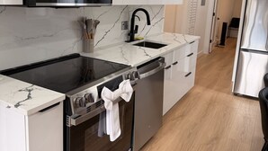 A modern kitchen with white cabinetry, a black stove, and a stainless steel refrigerator.
