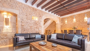 A cozy living area with stone walls, leather sofas, and a wooden coffee table. - CA'S MERCADER (ALGAIDA) - Beautiful rustic house with a private pool, perfect for cyclists (Algaida)