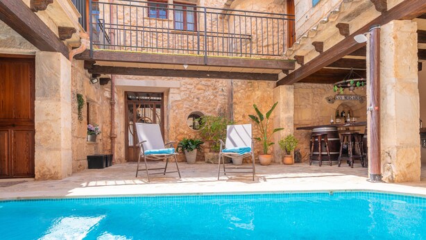 A pool area with lounge chairs, a bar, and a stone building with a balcony. - CA'S MERCADER (ALGAIDA) - Beautiful rustic house with a private pool, perfect for cyclists (Algaida)