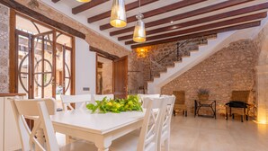 A dining area with a white table and chairs, a staircase, and stone walls. - CA'S MERCADER (ALGAIDA) - Beautiful rustic house with a private pool, perfect for cyclists (Algaida)