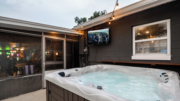 Un jacuzzi con un televisor montado en la pared, una ventana y luces colgantes.